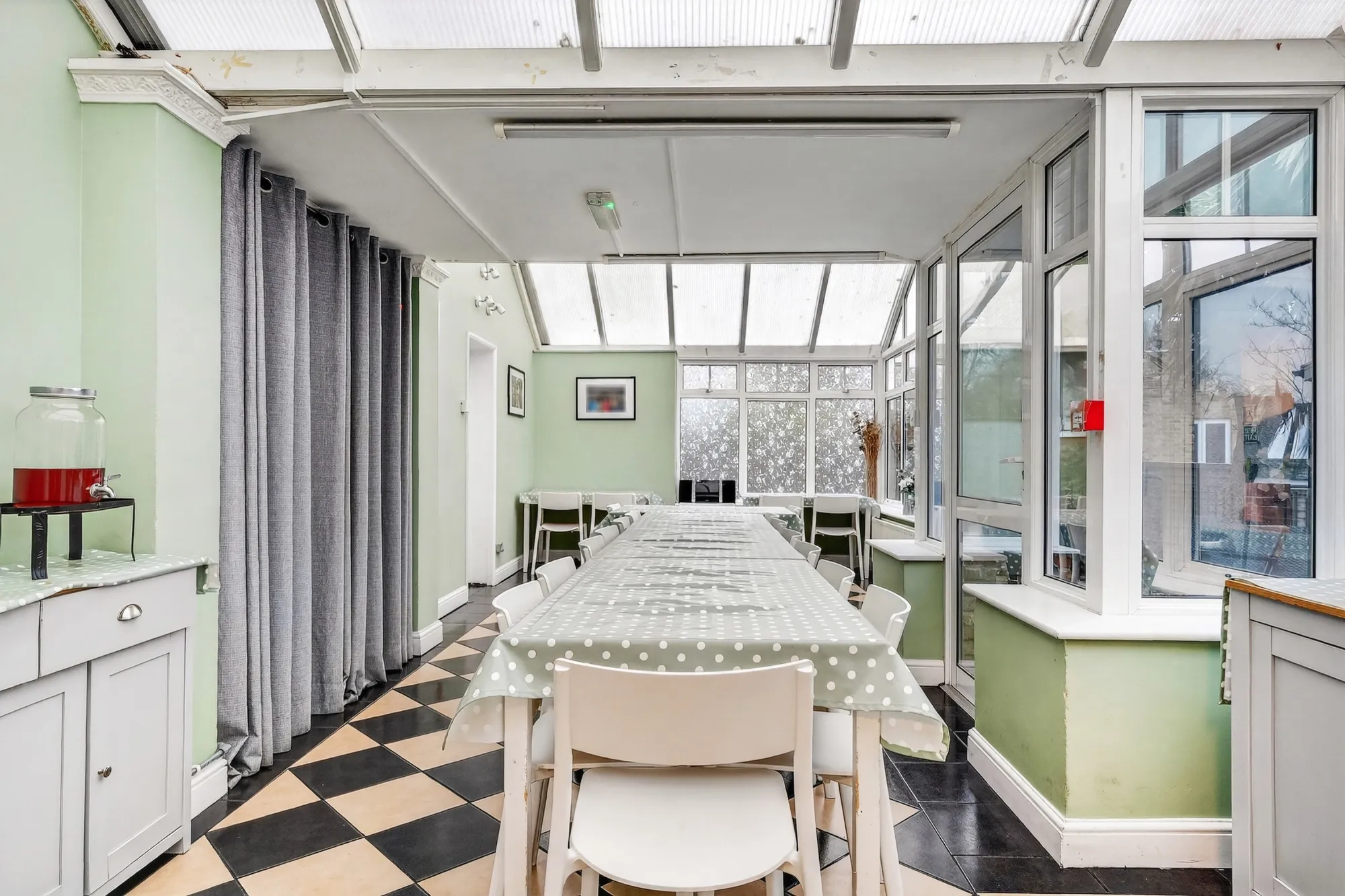 Bright communal dining room with long dining table, conservatory roof and natural light at Pinfold Care Home
