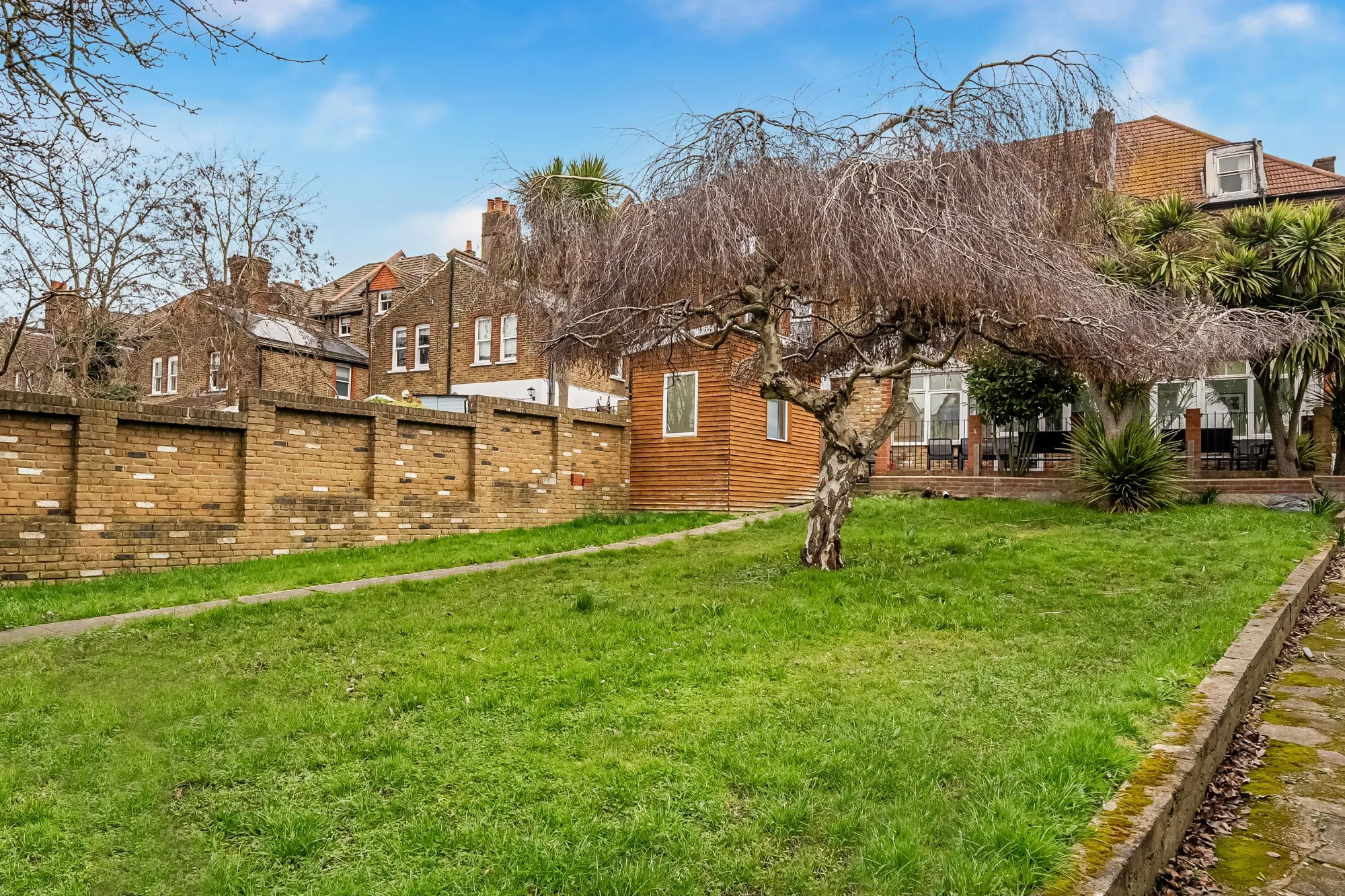 Large secure rear garden with lawn, mature trees and outdoor space for residents at Pinfold Care Home