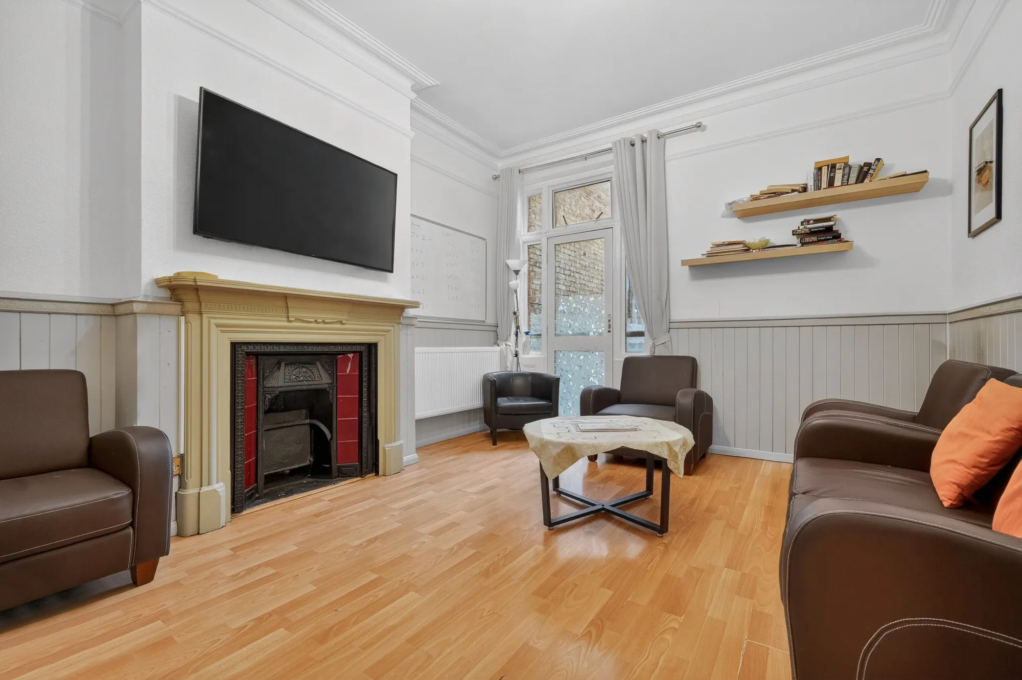 Comfortable shared lounge with fireplace, seating area and television for residents at Pinfold Care Home